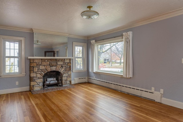 unfurnished living room with a textured ceiling, light wood-type flooring, a baseboard radiator, and a healthy amount of sunlight