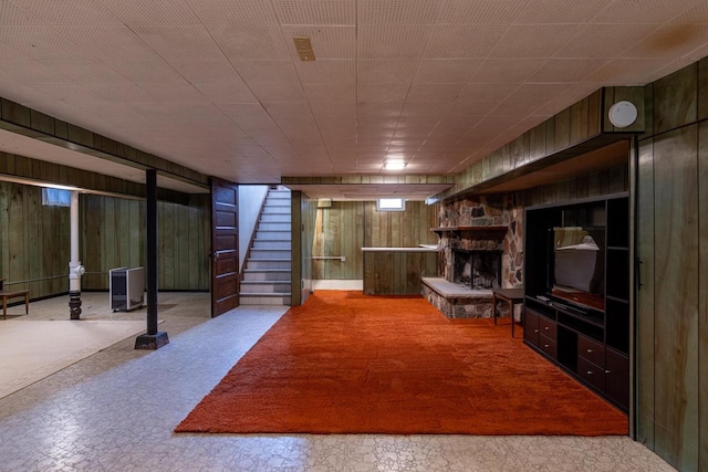 basement featuring wood walls and a stone fireplace