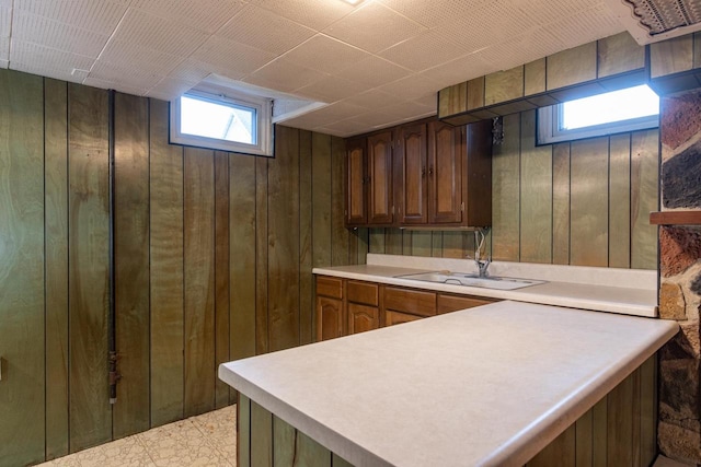 kitchen with wood walls, light tile patterned floors, and sink