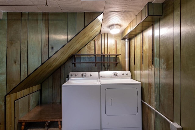 clothes washing area featuring wooden walls and washer and dryer