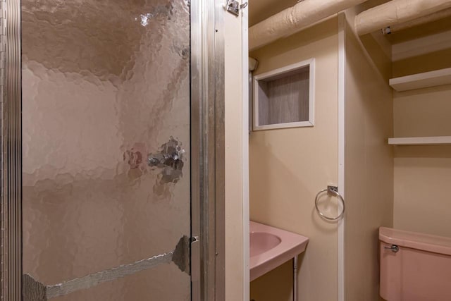 bathroom featuring toilet and a shower with door