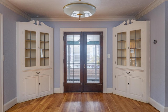 doorway featuring a textured ceiling, ornamental molding, light hardwood / wood-style flooring, and french doors