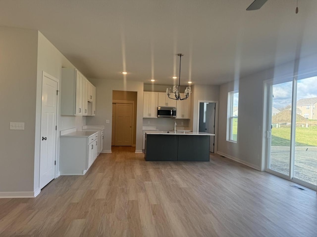 kitchen with light hardwood / wood-style flooring, white cabinets, and hanging light fixtures