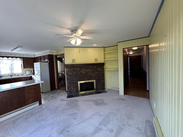 unfurnished living room featuring ceiling fan, a baseboard heating unit, light colored carpet, and a brick fireplace