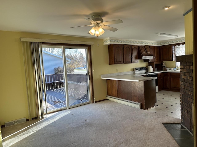 kitchen featuring kitchen peninsula, light carpet, electric range oven, dark brown cabinetry, and a baseboard radiator