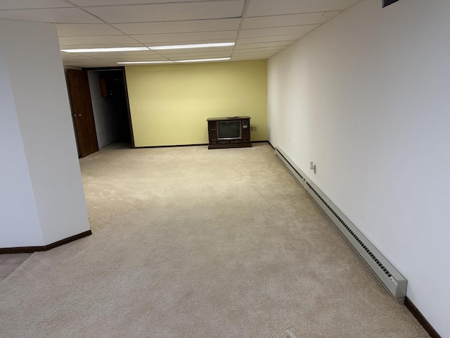 empty room featuring baseboard heating, a paneled ceiling, and light carpet