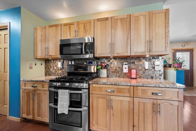 kitchen with backsplash, dark hardwood / wood-style flooring, light stone counters, and appliances with stainless steel finishes