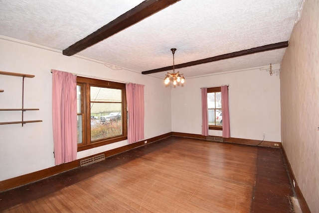 empty room featuring beamed ceiling, wood-type flooring, and a textured ceiling