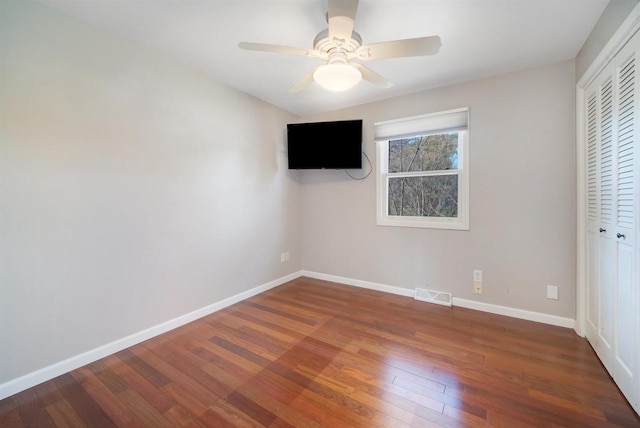 unfurnished bedroom featuring ceiling fan, dark hardwood / wood-style flooring, and a closet