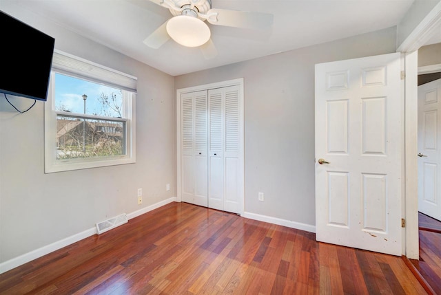 unfurnished bedroom with ceiling fan, a closet, and dark hardwood / wood-style floors