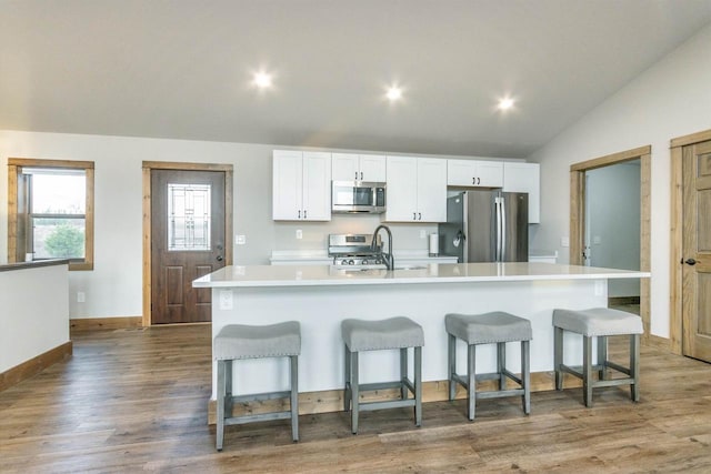 kitchen featuring white cabinets, a breakfast bar area, vaulted ceiling, a large island, and stainless steel appliances