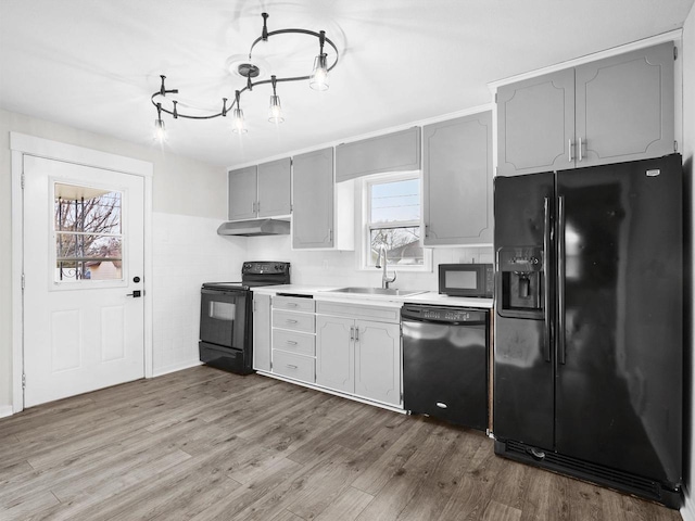 kitchen with black appliances, a healthy amount of sunlight, gray cabinetry, and sink