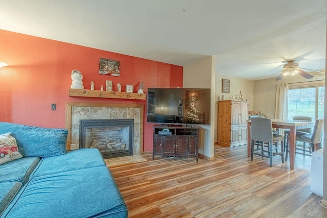 living room featuring a fireplace, ceiling fan, and light hardwood / wood-style flooring