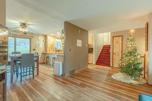 interior space with ceiling fan, oven, light wood-type flooring, and kitchen peninsula