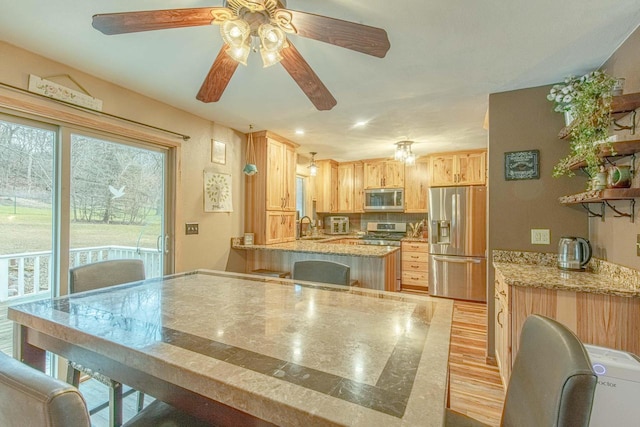 kitchen featuring sink, light brown cabinets, light stone counters, appliances with stainless steel finishes, and light wood-type flooring