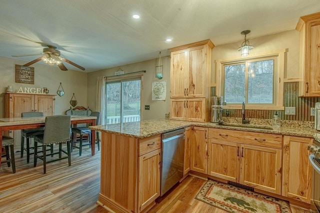 kitchen with light stone countertops, sink, decorative light fixtures, dishwasher, and light hardwood / wood-style floors