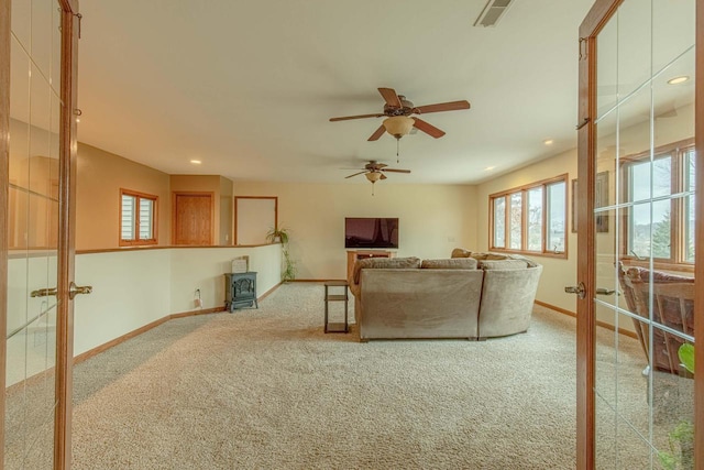 carpeted living room featuring french doors, a wood stove, and ceiling fan