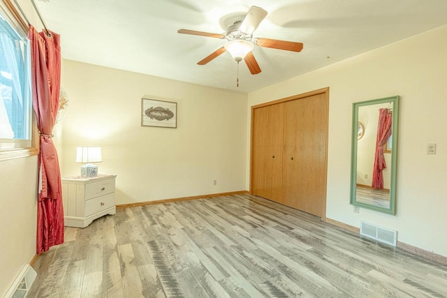 unfurnished bedroom with multiple windows, a closet, light hardwood / wood-style floors, and ceiling fan