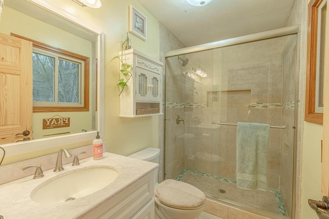 bathroom featuring vanity, a shower with shower door, and toilet