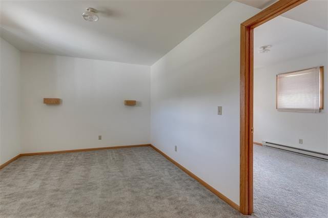 carpeted empty room featuring baseboard heating