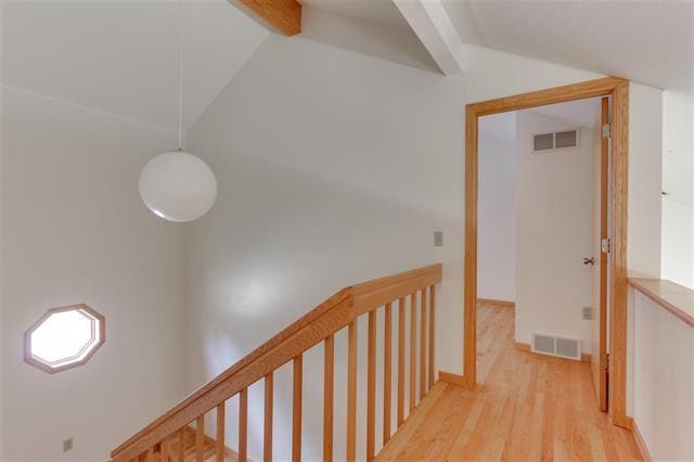 hallway with lofted ceiling with beams and light hardwood / wood-style floors