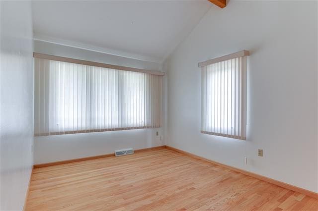 empty room with vaulted ceiling with beams and hardwood / wood-style flooring