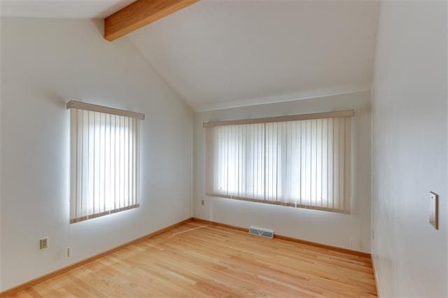 spare room with lofted ceiling with beams and hardwood / wood-style flooring