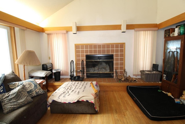 living room featuring hardwood / wood-style floors, vaulted ceiling, and a tiled fireplace