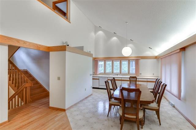 dining area with light hardwood / wood-style floors and high vaulted ceiling