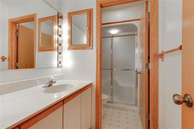 bathroom featuring vanity, toilet, and a shower with door