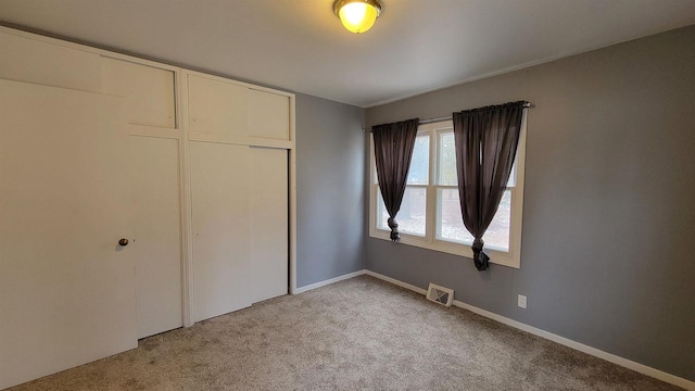 unfurnished bedroom with light colored carpet and a closet