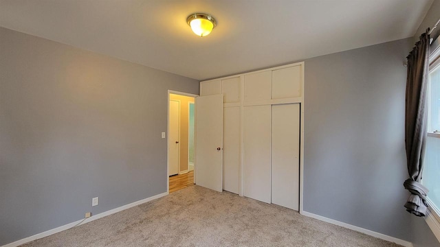 unfurnished bedroom featuring light colored carpet and a closet