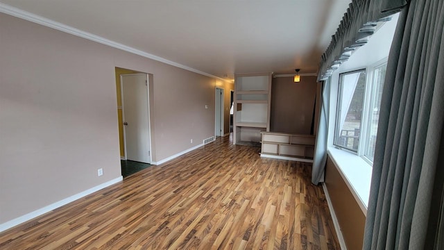 unfurnished living room with wood-type flooring, plenty of natural light, and ornamental molding