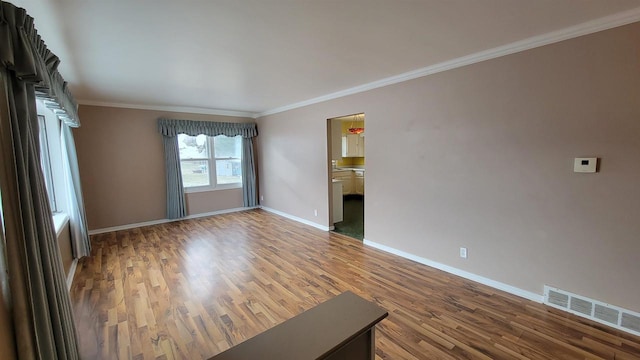 unfurnished living room featuring wood-type flooring and crown molding