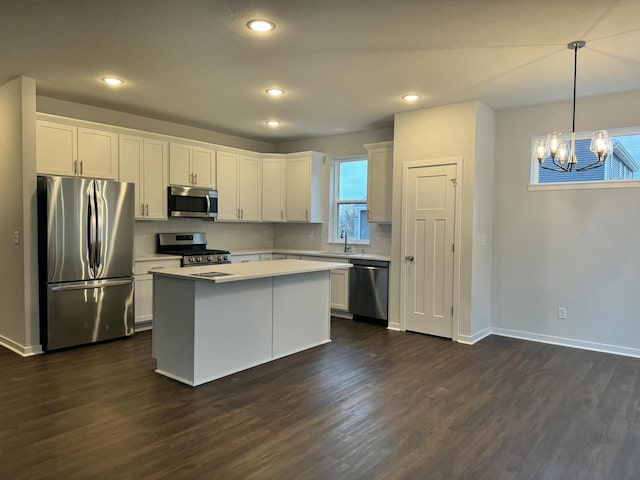 kitchen featuring dark hardwood / wood-style flooring, stainless steel appliances, white cabinets, a kitchen island, and hanging light fixtures