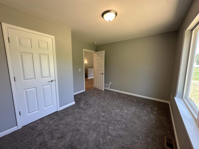 unfurnished bedroom featuring dark colored carpet and a closet