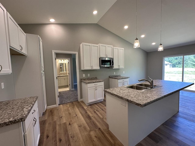 kitchen featuring a kitchen island with sink, sink, decorative light fixtures, white cabinetry, and lofted ceiling