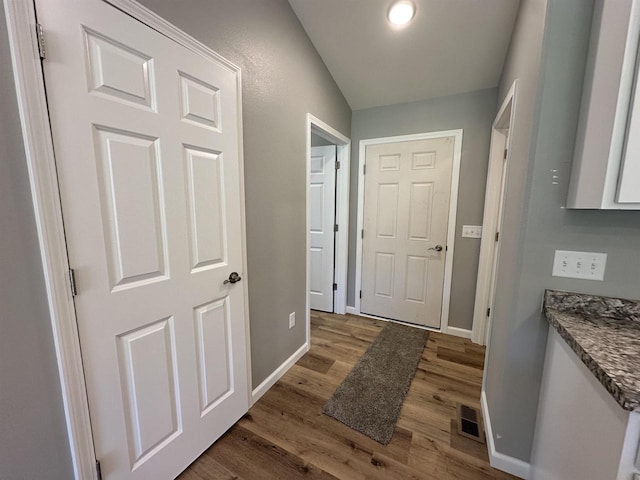 doorway to outside with lofted ceiling and wood-type flooring