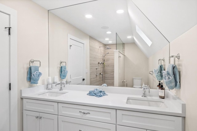 bathroom with tiled shower, vanity, toilet, and vaulted ceiling with skylight