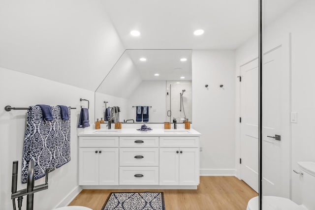 bathroom with vanity, vaulted ceiling, hardwood / wood-style flooring, toilet, and an enclosed shower