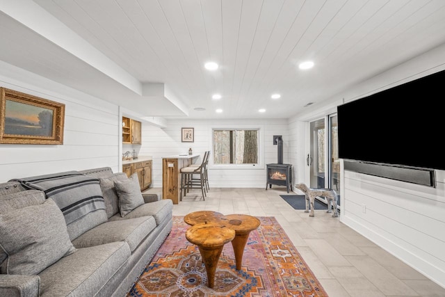 living room featuring a wood stove and wooden walls