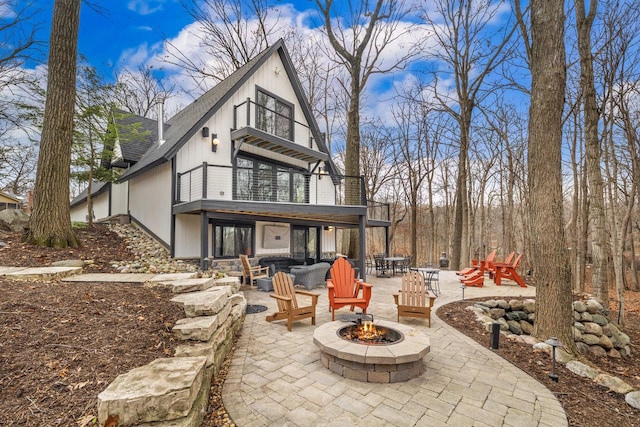 rear view of house with a patio area, a balcony, and an outdoor fire pit