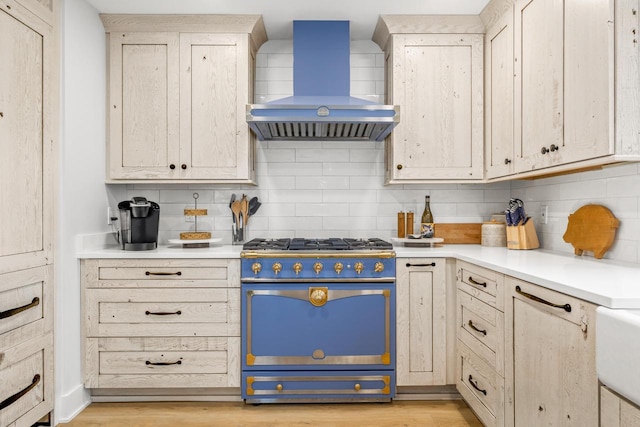 kitchen featuring backsplash, light hardwood / wood-style floors, high end stainless steel range, and wall chimney range hood