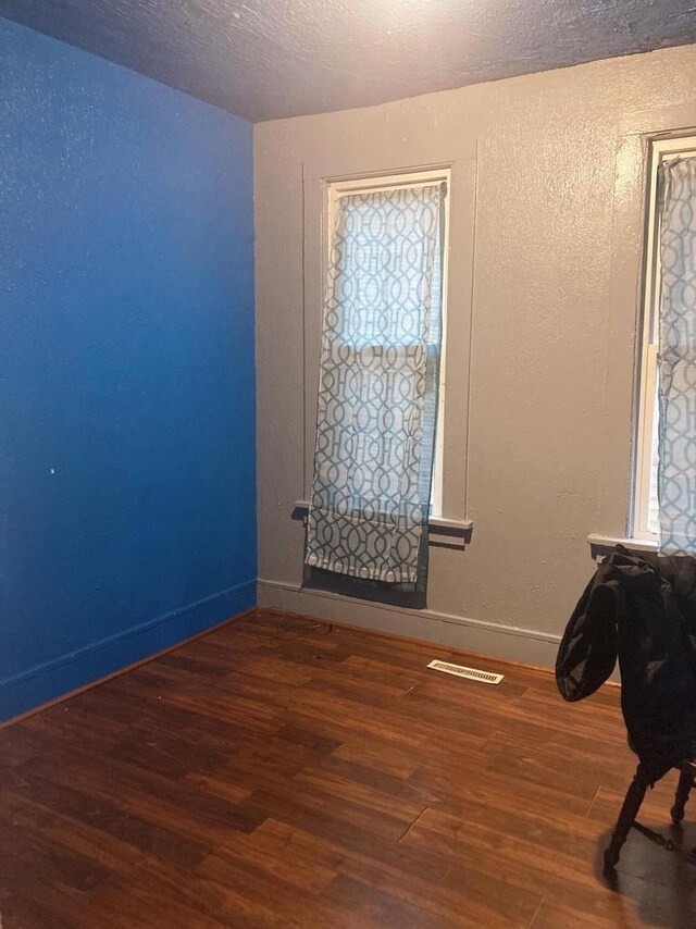 spare room featuring a textured ceiling and dark hardwood / wood-style floors