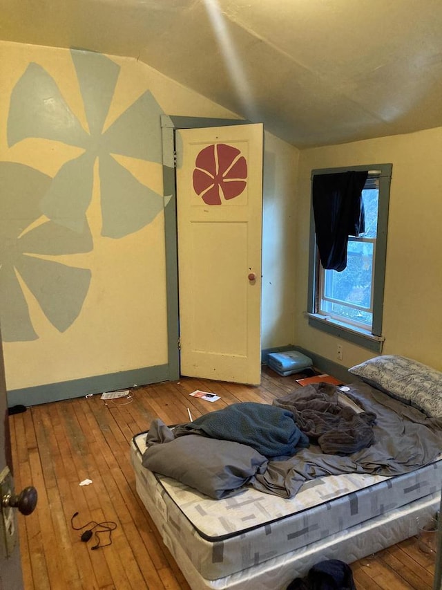 unfurnished bedroom featuring light wood-type flooring and lofted ceiling