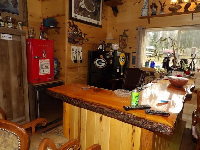 bar featuring black refrigerator and wood walls