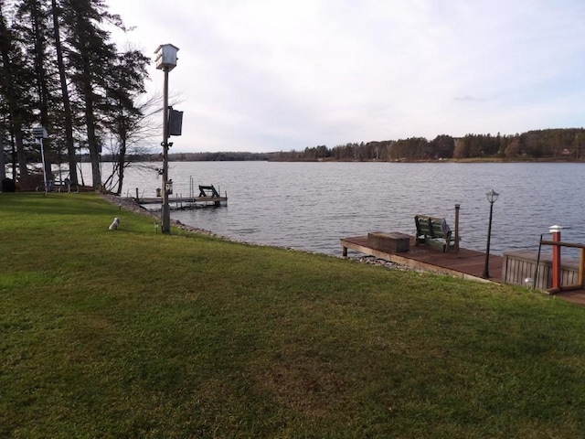 view of dock with a water view and a lawn