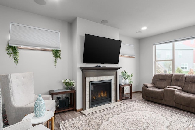 living room with a tile fireplace and light hardwood / wood-style floors