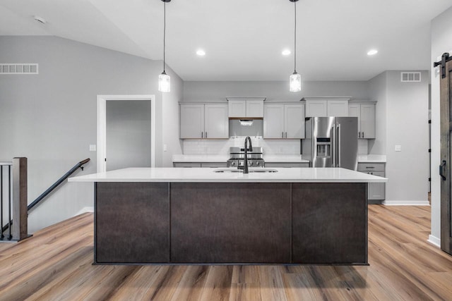 kitchen featuring stainless steel refrigerator with ice dispenser, sink, pendant lighting, hardwood / wood-style flooring, and lofted ceiling