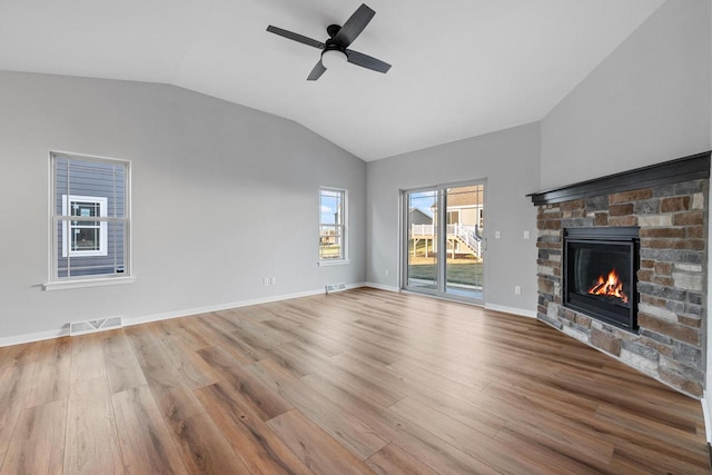 unfurnished living room with light hardwood / wood-style floors, a stone fireplace, ceiling fan, and lofted ceiling